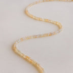 The Opal Beaded Necklace is arranged in a zigzag pattern on a light, neutral background, showcasing the free-spirited charm of bohemian jewelry.