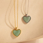 Two Aventurine Heart Necklaces—one on a gold chain, one on a silver chain—are displayed against a beige background.