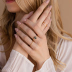 Woman with long blonde hair showcases the Agate Teardrop Ring in 18K Gold, pairing it with pale pink nail polish and gold rings near her face.