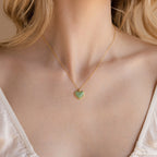 A woman, shown from the shoulders up, wears the Aventurine Heart Necklace—a gold chain featuring a heart-shaped aventurine gemstone pendant.
