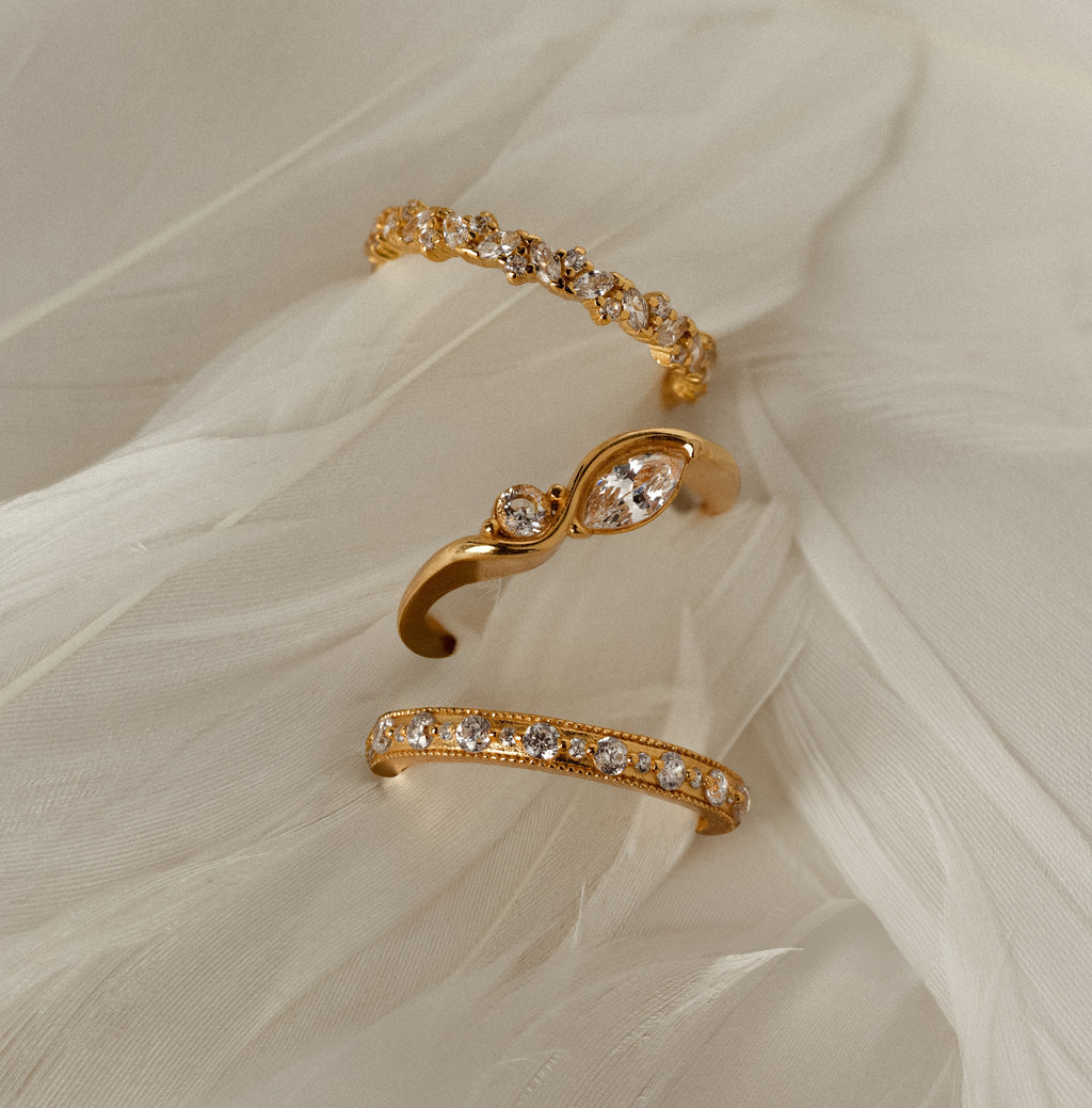 The Toi et Moi Infinity Birthstone Ring sparkles on a soft, feather-like white fabric background.