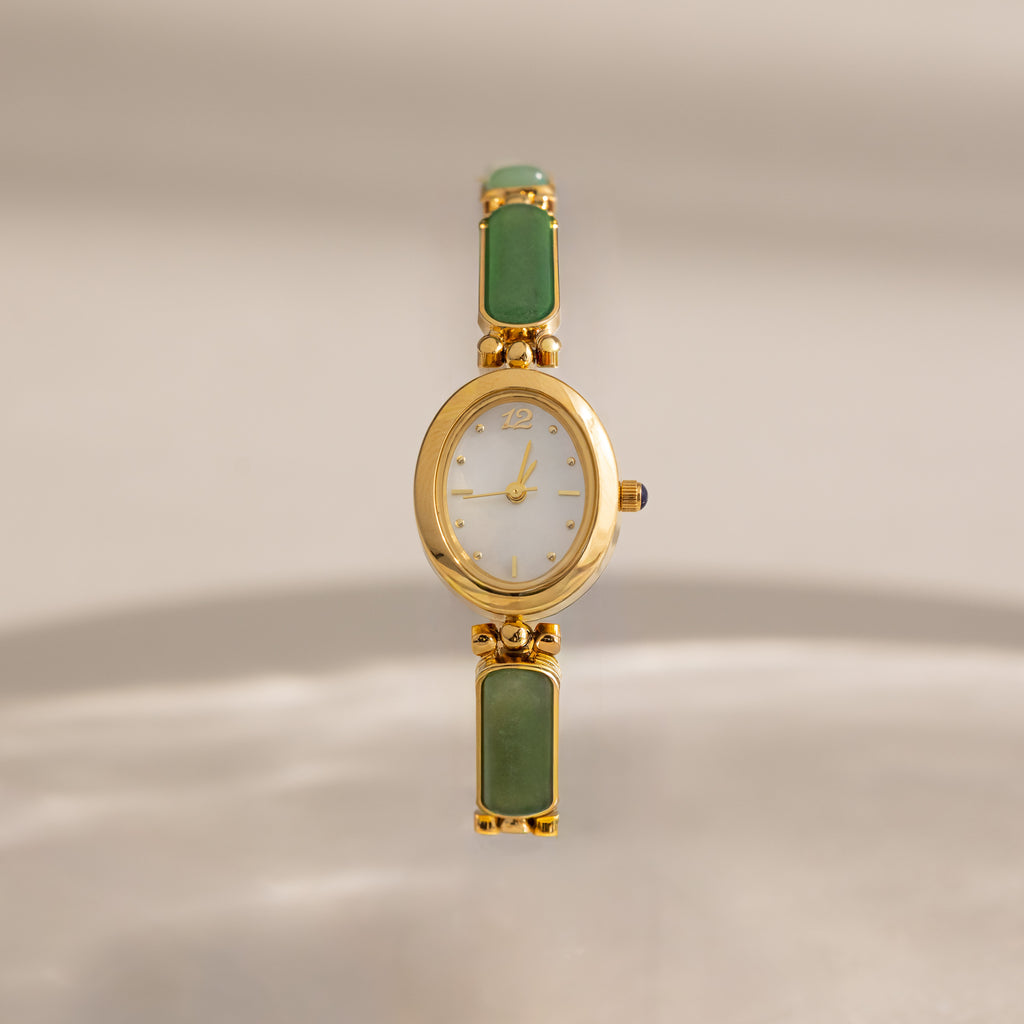 Our Jade Band Timepiece with a white dial and green jade rectangular inlay stones on the bracelet, centered against a soft beige background.