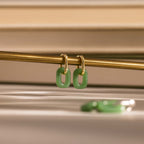 Gold hoop earrings with rectangular jade link drops hanging from a brass bar.