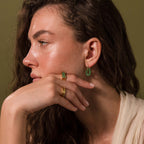 Woman wearing modern gold hoop earrings with rectangular jade link drops.