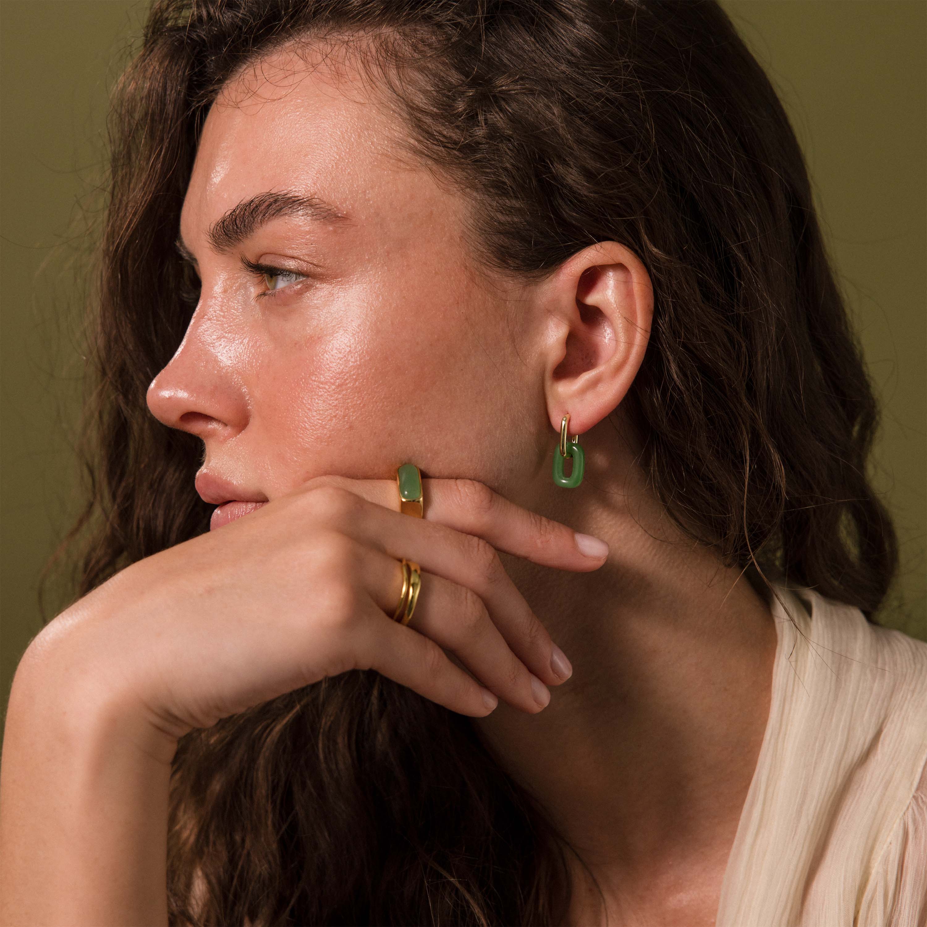 Woman wearing modern gold hoop earrings with rectangular jade link drops.