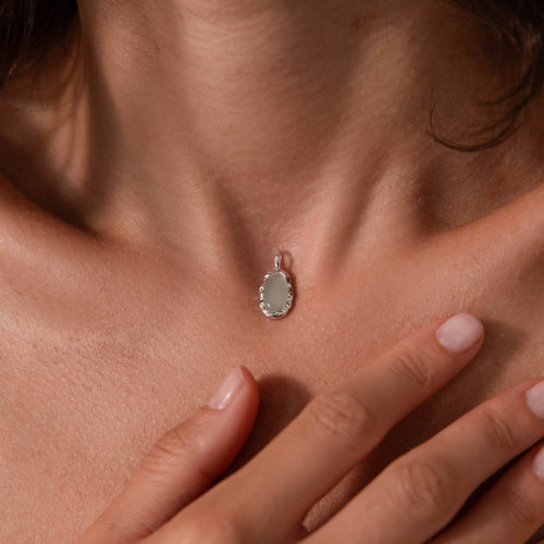 Aura Seafoam Charm: oval seafoam stone in an organic silver setting on a woman's neck.