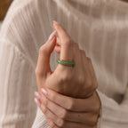 A hand with manicured nails wears the Haven Jade Spinner Ring, spinning the mindful jewelry with the other hand.