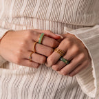 Close-up of hands wearing a gold band and the Haven Jade Spinner Ring, paired with a white textured long-sleeve top—an elegant display of mindful jewelry.