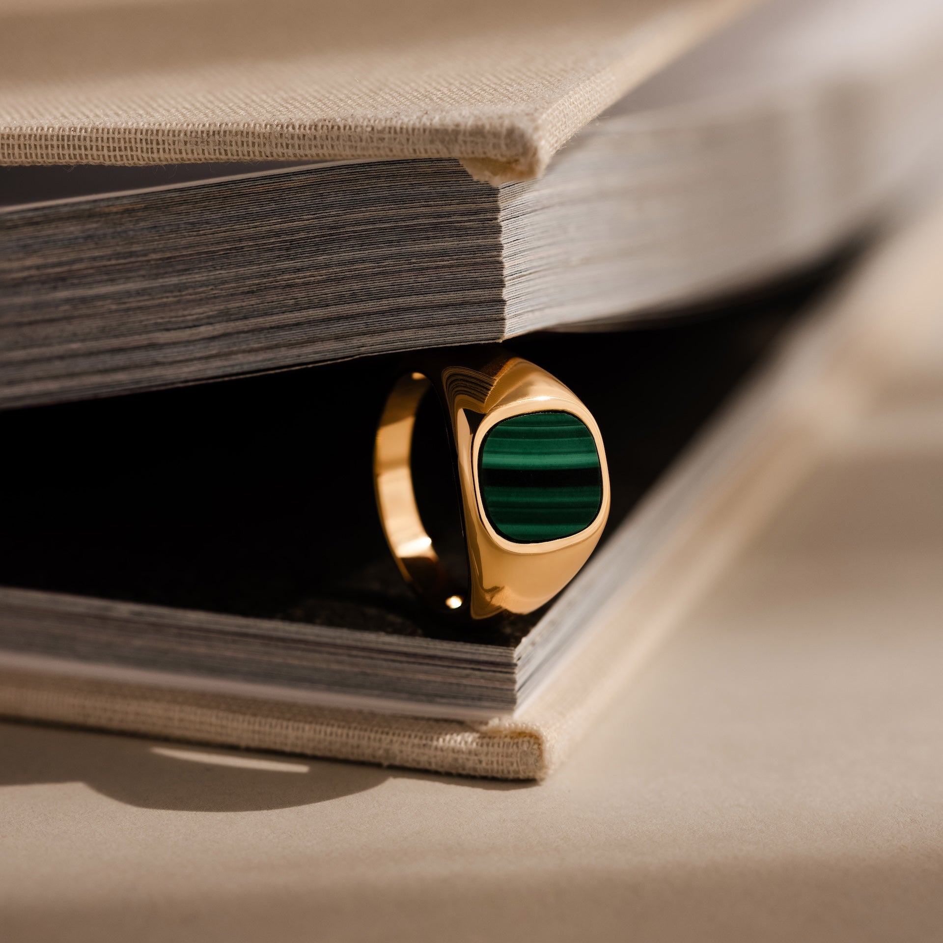 A Malachite Signet Ring is placed between the pages of an open book.