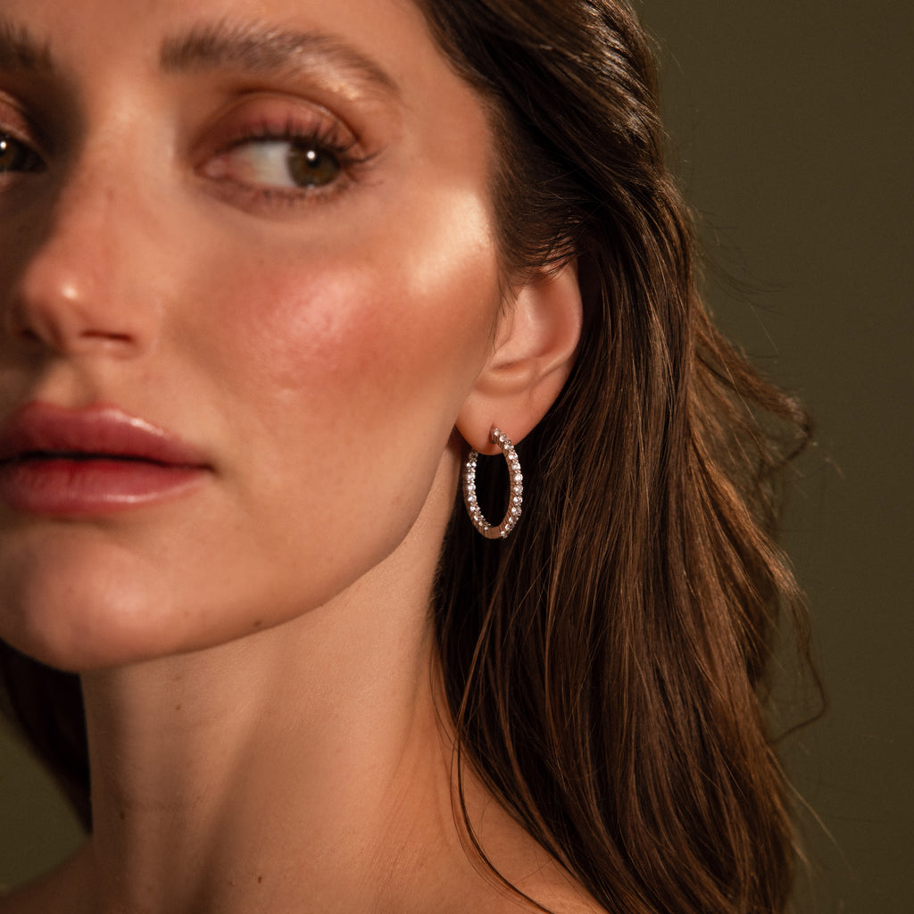 Woman with wavy brown hair wearing Inside Out Diamond Hoops in Silver, looking to the side with a neutral expression.