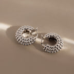 Beaded Dome Hoops in Silver—these statement earrings feature a bold beaded texture, shown on a beige surface with soft lighting for a modern, stylish look.