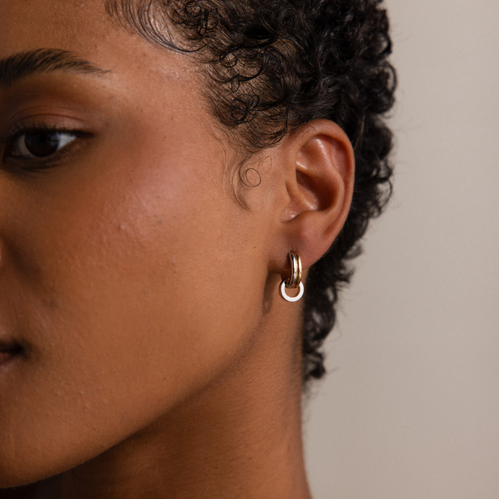Close-up of a person with short curly hair wearing Mixed Metal Circle Hoops—small, versatile earrings featuring mixed metals and a white accent, ideal for anyone who loves stylish, adaptable jewelry.