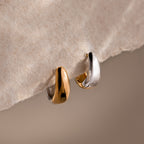 Bold Mixed Metal Huggies—two small, chunky gold and silver earrings—create a contemporary look, shown on textured beige paper.