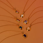 Eight necklaces, including the Ribbed Amethyst Pendant Necklace, feature vibrant gemstones and are displayed in a circular arrangement on an orange background.