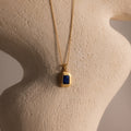 Ribbed Sapphire Pendant Necklace with a ribbed gold chain and a blue rectangular pendant, showcased on a textured beige sculpture.