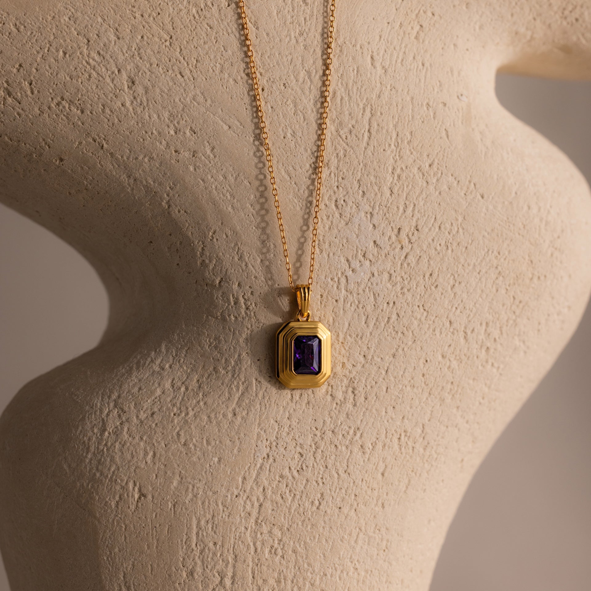The Ribbed Amethyst Pendant Necklace is displayed elegantly on a mannequin.