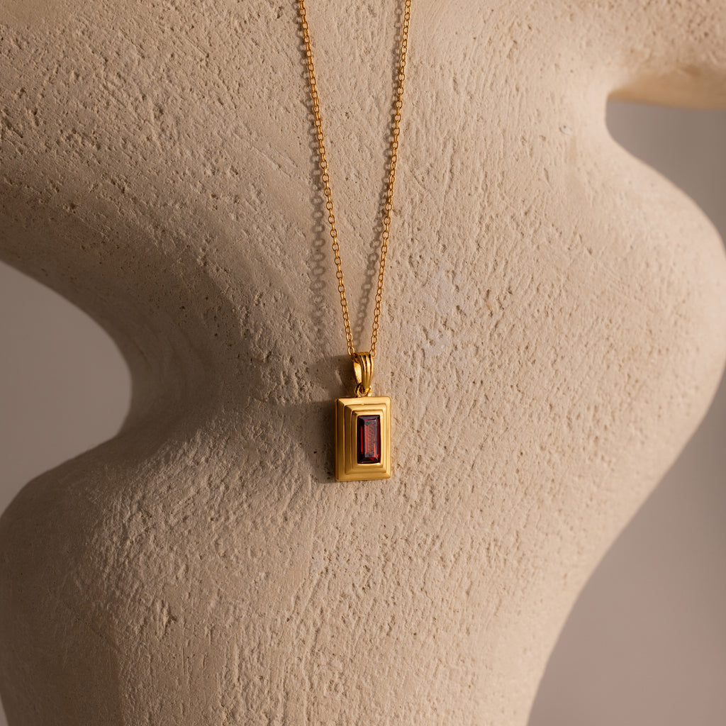 Ribbed Garnet Pendant Necklace featuring a rectangular garnet pendant displayed on a textured, neutral-colored sculpture.