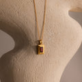 Ribbed Garnet Pendant Necklace featuring a rectangular garnet pendant displayed on a textured, neutral-colored sculpture.