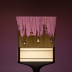 A large paintbrush with pink paint displays five gold necklace pendants, including the shimmering Mixed Alexandrite Capsule Pendant Necklace, hanging elegantly from its bristles.