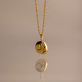 The Mixed Topaz Capsule Pendant Necklace features a gold design with three embedded topaz stones on a round charm—a timeless birthstone piece for personalizing your style, shown against a neutral background.