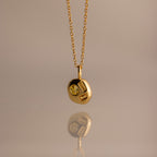 The Mixed Topaz Capsule Pendant Necklace features a gold design with three embedded topaz stones on a round charm—a timeless birthstone piece for personalizing your style, shown against a neutral background.