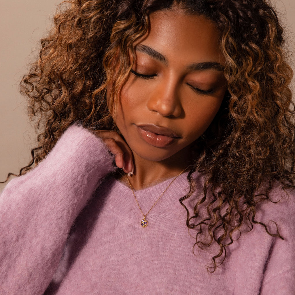 Woman with curly hair in a fuzzy lavender sweater, eyes closed, wearing the Mixed Topaz Capsule Pendant Necklace that glimmers softly against her skin.