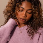 Woman with curly hair in a fuzzy lavender sweater, eyes closed, wearing the Mixed Topaz Capsule Pendant Necklace that glimmers softly against her skin.