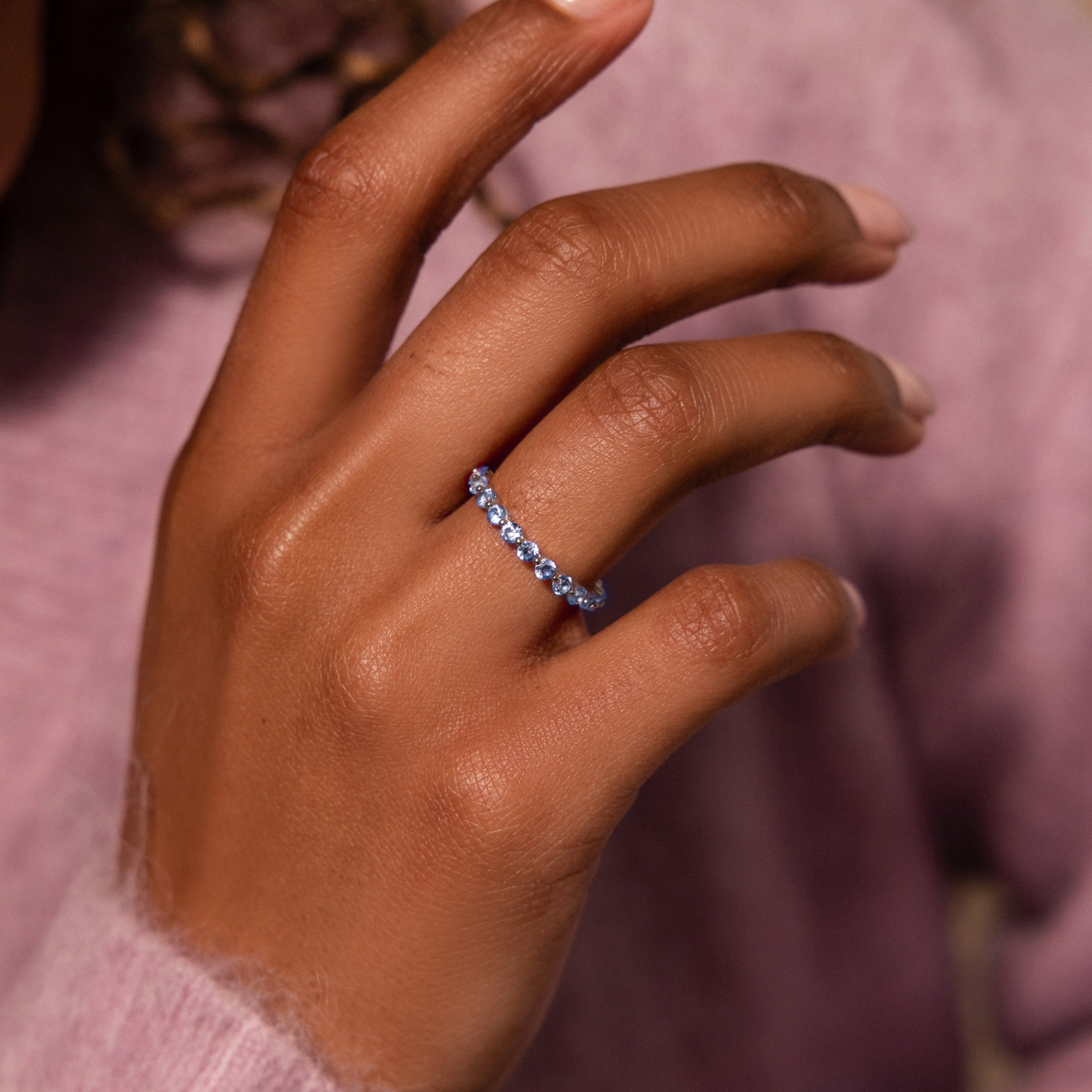 A hand wearing the Lace Eternity Sapphire Ring, with a soft purple sweater in the background.