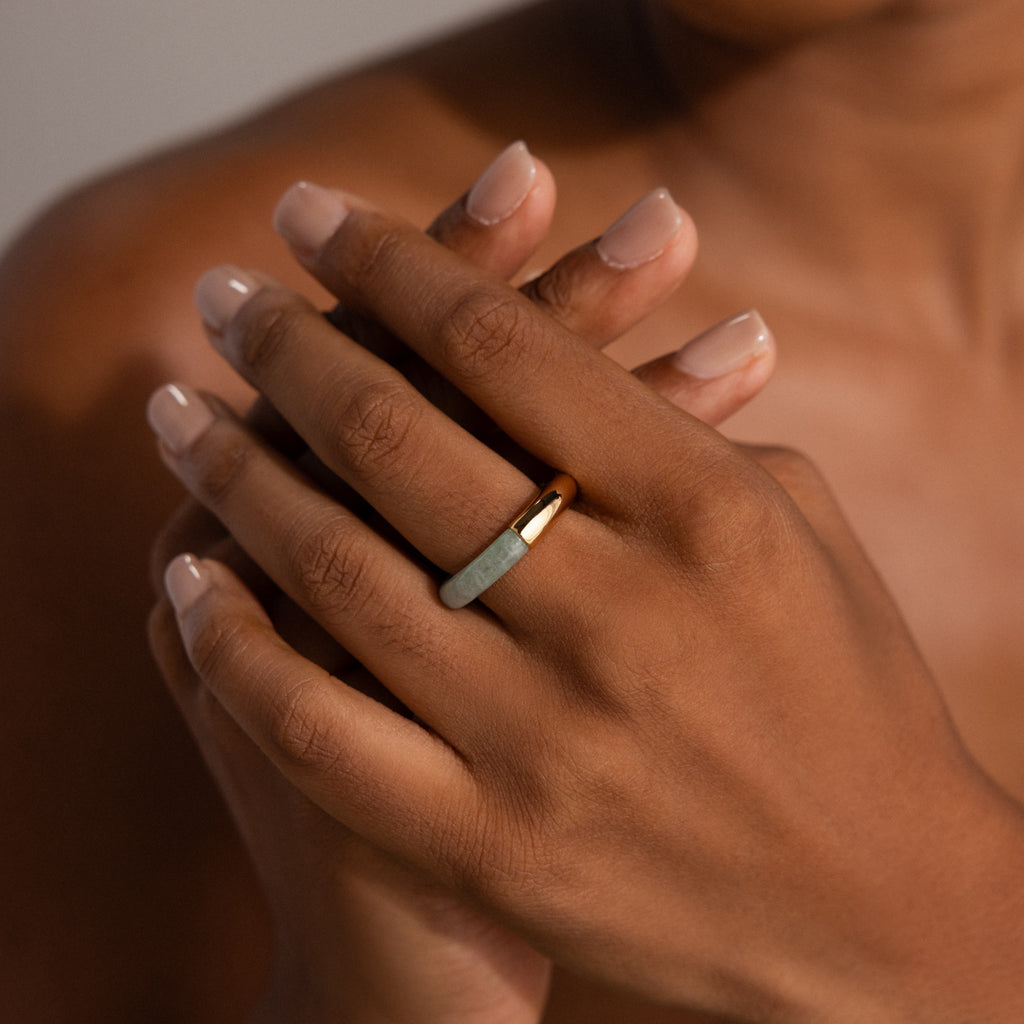 A close-up of hands with nude nails wearing the Half Jade Ring on the middle finger, highlighting this elegant statement jewelry.