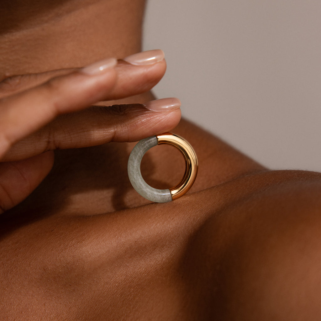 A person holds the Half Jade Ring, a striking statement jewelry piece, on their shoulder.