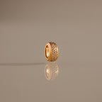 The Bold Pave Dome Charm in 18K Gold features rows of sparkling diamonds, elegantly displayed upright on a reflective, neutral surface for a sophisticated presentation.
