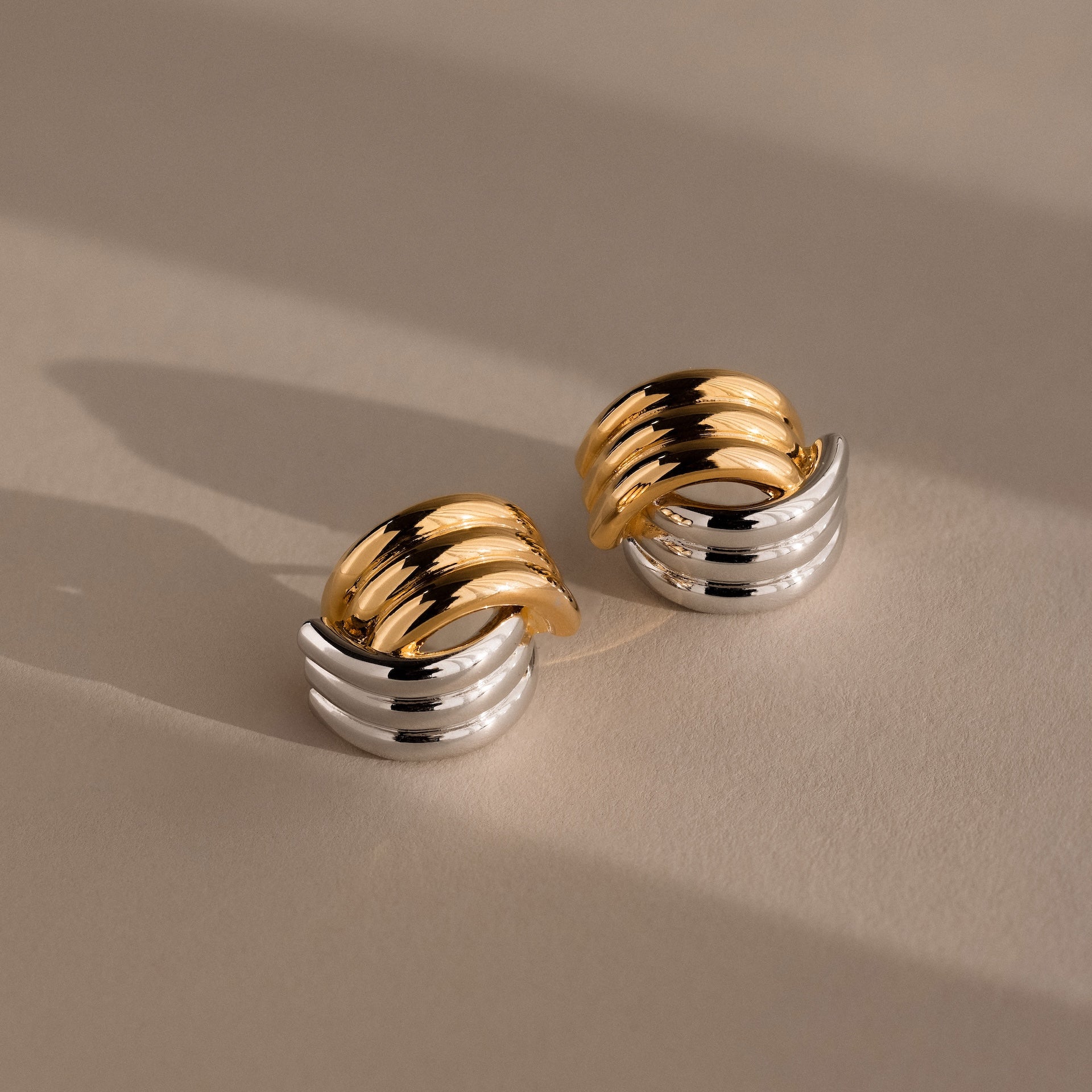 The Ribbed Mixed Metal Studs in gold and silver feature a sculpted, ribbed design, making these earrings a standout accessory against any neutral backdrop.