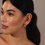 A woman with long dark hair wears the Duo Pave Dome Studs, gazing to the side with a neutral expression—these earrings add an elegant accent to her everyday look.