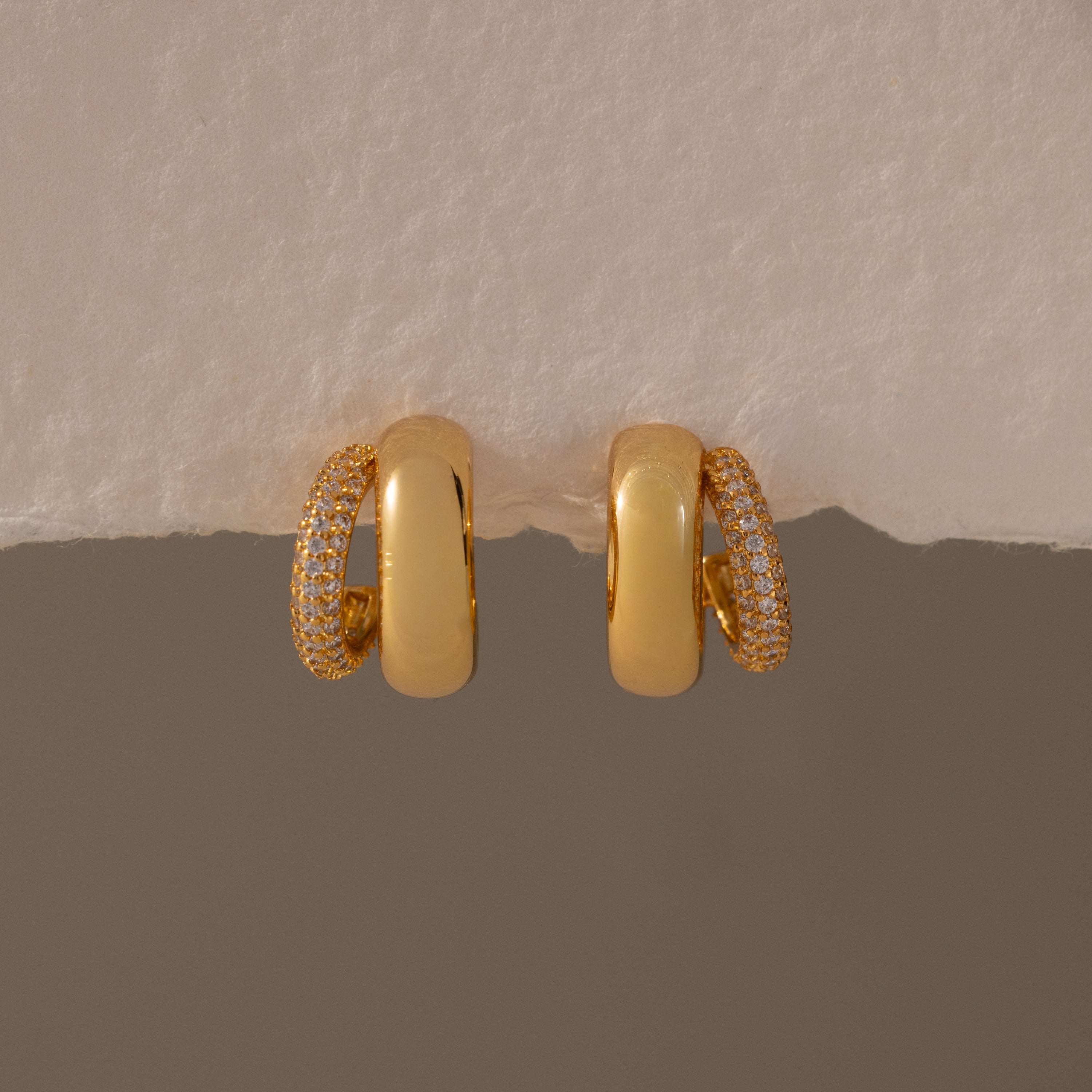 Duo Pave Dome Studs in 18K Gold feature one half plain and the other half pavé-set with clear crystals, making them perfect for everyday wear. Shown against a neutral background.