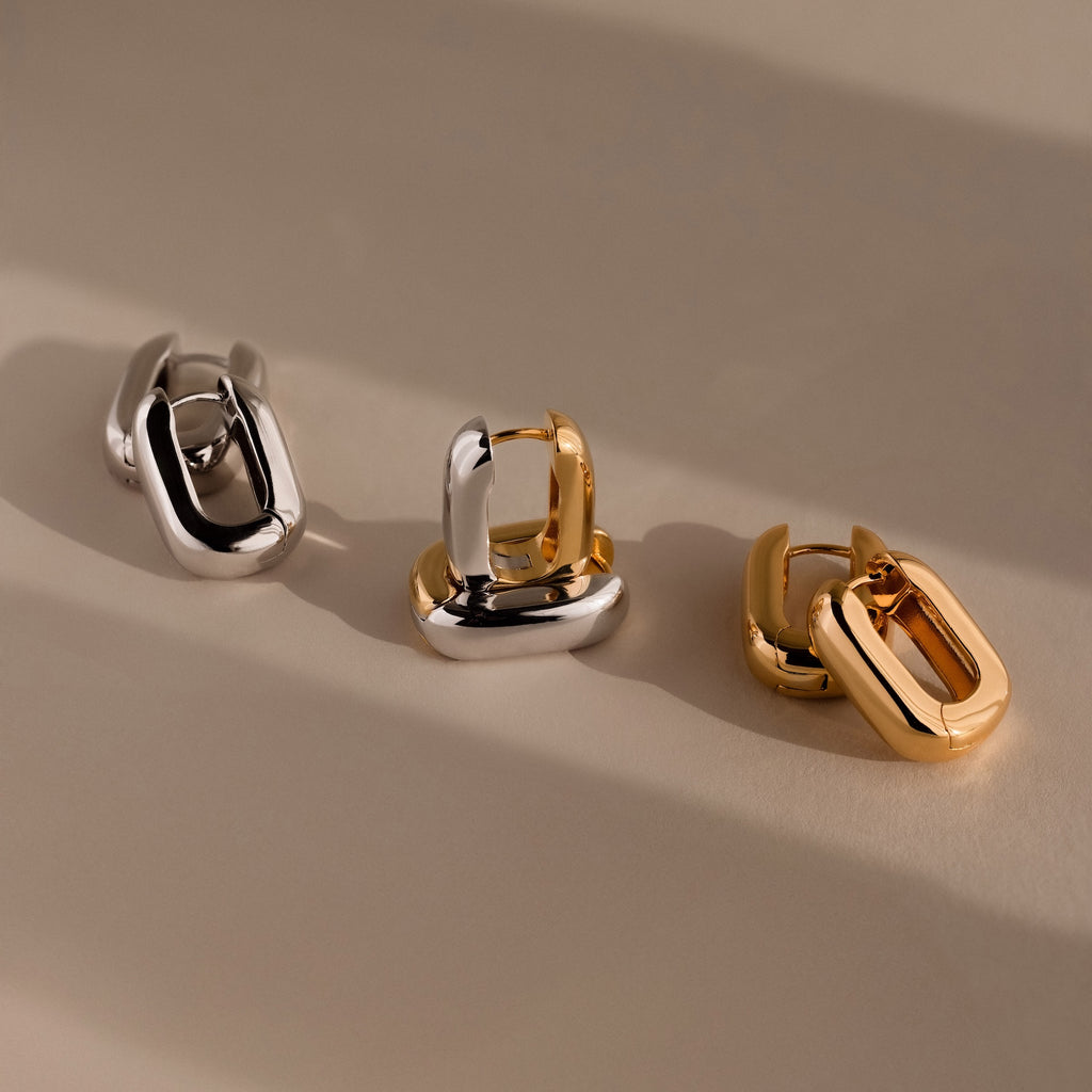 Bold Link Hoops are showcased in three chunky, interlocking designs—silver, mixed silver-gold, and gold—highlighting their modern style against a neutral background.