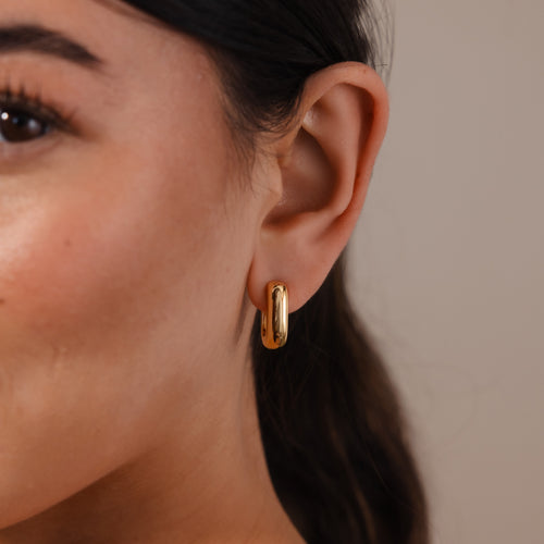 Close-up of a woman's ear wearing Bold Link Hoops in 18K Gold—sleek, polished earrings ideal for lovers of modern style without the weight of chunky hoops.