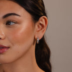 Woman with smooth skin wears Bold Link Hoops in White Gold—sleek modern earrings—with her hair pulled back, set against a neutral background.