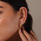 Close-up of a woman's ear adorned with Bold Link Hoops in 18K Gold, her hand gently touching the earlobe.