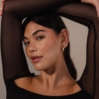 A woman with long dark hair poses with her arm raised, wearing a black mesh top and Bold Link Hoops, giving her look a modern edge with these statement earrings.
