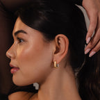 A woman with smooth skin and dark hair poses with her hand near her head, showcasing a statement look highlighted by Bold Link Hoops in Mixed Metal.