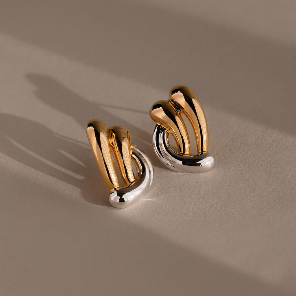 Mixed Metal Raindrop Studs feature gold and silver abstract sculptural earrings with a curved design, adding a modern touch to any look.
