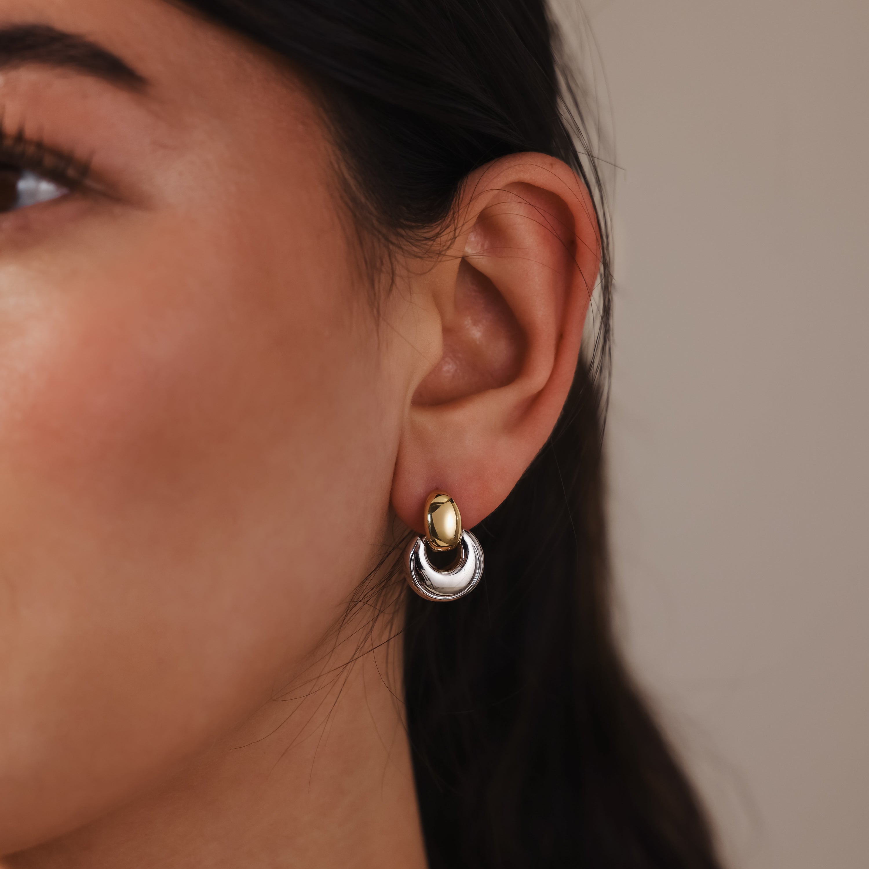 Close-up of a woman's ear adorned with Eclipse Dome Studs in Mixed Metal—two-tone gold and silver earrings that embody the essence of modern jewelry.