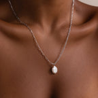 Silver paperclip chain necklace with a pearl pendant on a woman's neck