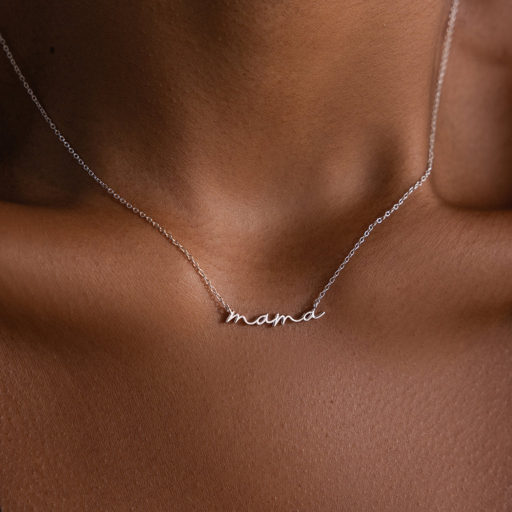 Silver dainty necklace with 'mama' pendant on a woman's neck