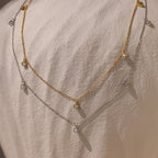Features two gold and silver necklace chains with clear gemstone accents, creating a modern, timeless accessory that adds elegant sparkle to any outfit.