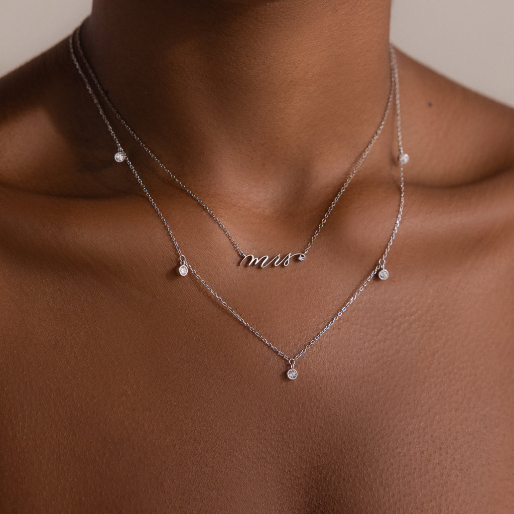 A Diamond Station Necklace graces the neck, its modern elegance making it a timeless accessory.