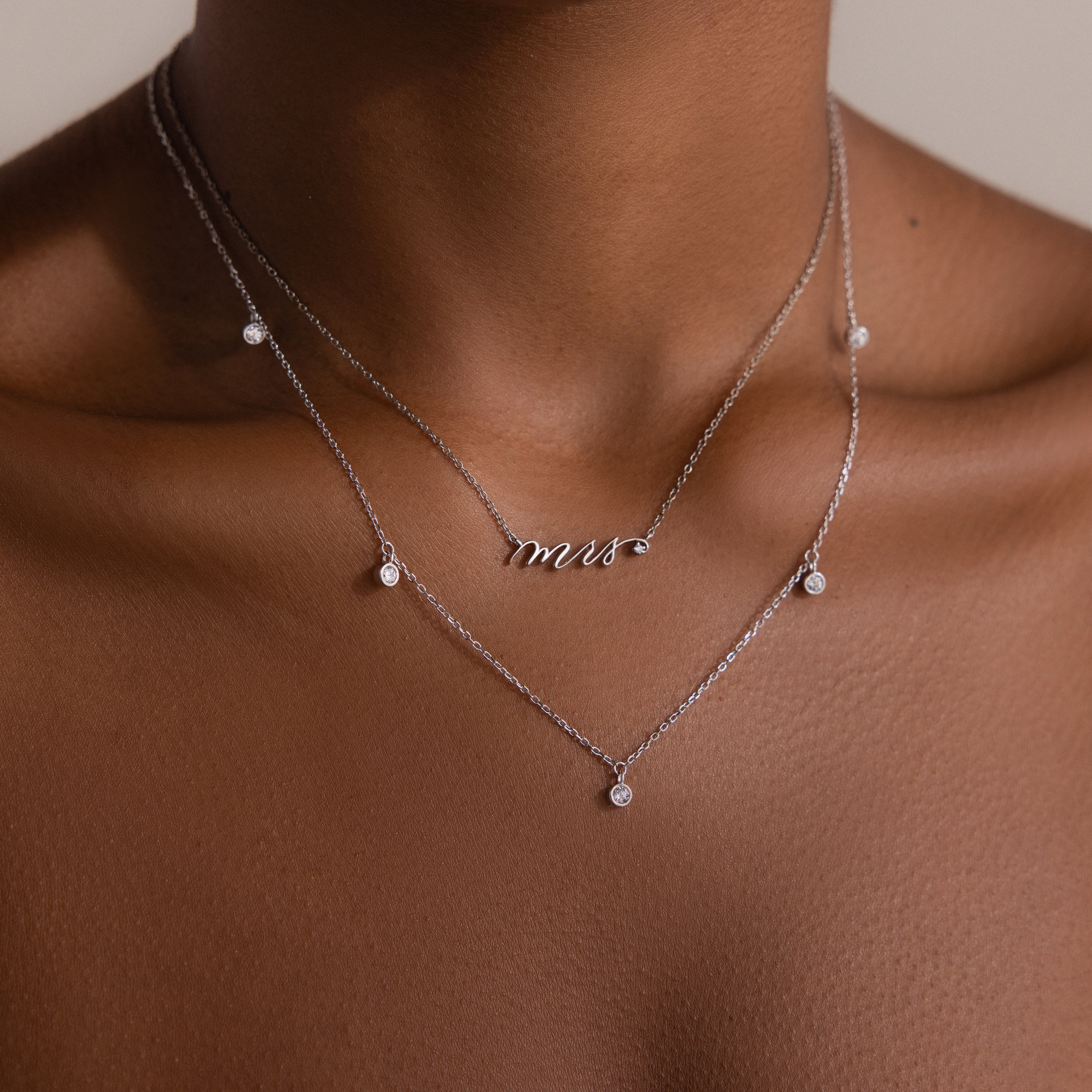 A Diamond Station Necklace graces the neck, its modern elegance making it a timeless accessory.