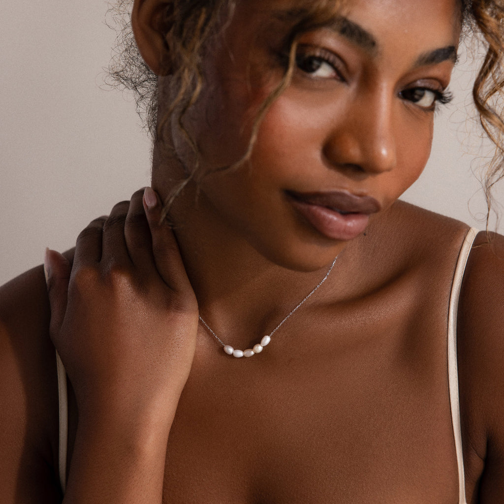 Woman with curly hair models the Pearl Bead Necklace in Silver with a white strap top—an elegant choice for thoughtful bridesmaids gifts or Mother’s Day presents.