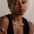 Woman with curly hair wearing a black sleeveless top and the Satellite Necklace in Silver—perfect for layering or adding an elegant touch when worn alone.