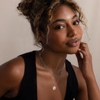 Smiling woman with curly hair wearing a black sleeveless top and the Linked Pendant Necklace in Silver, softly layered for a dainty look.